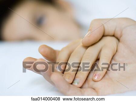 Child lying in bed, father's hand holding child's View Large Photo Image Stock Photo - Child lying in bed, father's hand holding child's. Fotosearch