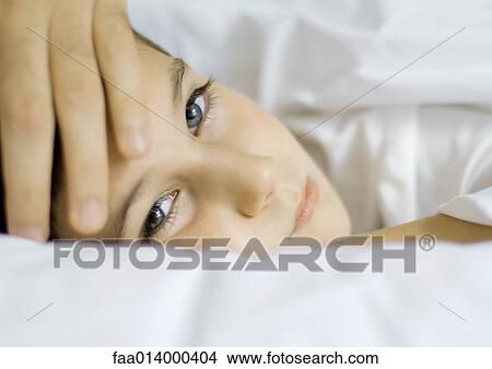 Picture - Child lying in bed with father's hand on forehead. Fotosearch