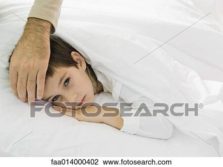 Child lying in bed with father's hand on forehead View Large Photo Image Stock Image - Child lying in bed with father's hand on forehead. Fotosearch