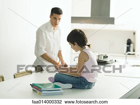 Child sitting on kitchen counter, doing homework, father in background View Large Photo Image Stock Image - Child sitting on kitchen counter, doing homework, father in background. Fotosearch