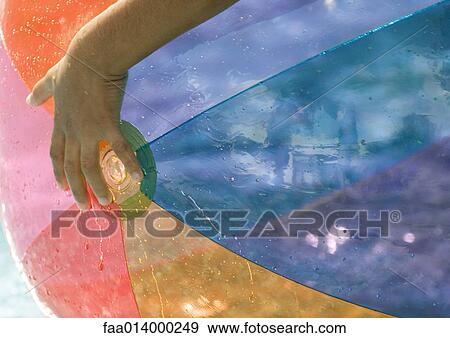 Stock Photo - Child's hand holding beach ball, close-up. Fotosearch