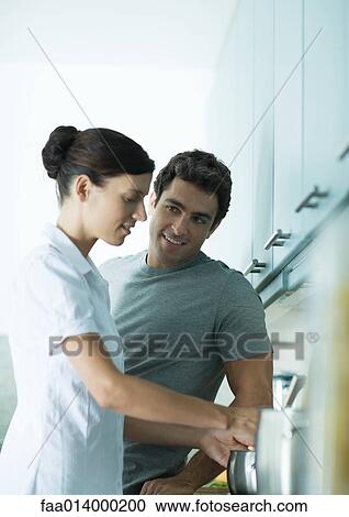 Stock Image - Couple cooking in kitchen together. Fotosearch