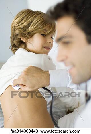 Stock Photo - Doctor holding stethoscope to boy's back. Fotosearch