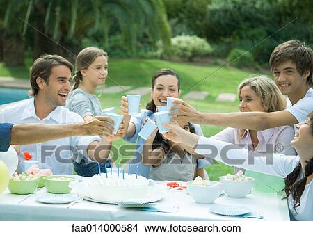 Picture - Family clinking cups over birthday cake. Fotosearch