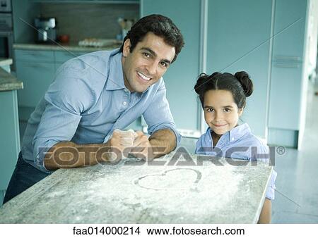 Father and daughter standing by counter with flour sprinkled on it, heart drawn in flour View Large Photo Image Picture - Father and daughter standing by counter with flour sprinkled on it, heart drawn in flour. Fotosearch