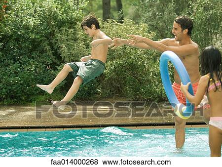 Stock Photo - Father throwing son in swimming pool. Fotosearch