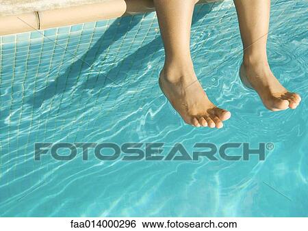 Stock Photograph - Feet dangling over swimming pool. Fotosearch