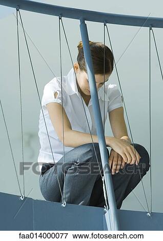 Female office worker crouching, head down, guard rail in foreground View Large Photo Image Stock Photo - Female office worker crouching, head down, guard rail in foreground. Fotosearch