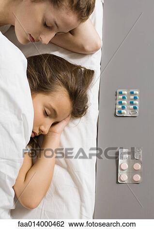 Girl and mother lying in bed, medicines by bed side in foreground View Large Photo Image Stock Image - Girl and mother lying in bed, medicines by bed side in foreground. Fotosearch