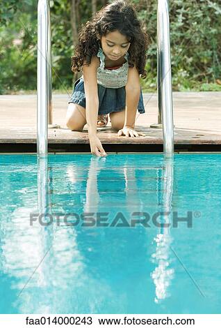 Girl crouching by edge of pool, touching surface of water View Large Photo Image Stock Image - Girl crouching by edge of pool, touching surface of water. Fotosearch