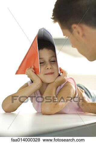 Girl holding notebook over head, turning toward father View Large Photo Image Stock Photo - Girl holding notebook over head, turning toward father. Fotosearch