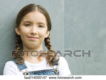 Stock Photo - Girl leaning against wall and smiling, head and shoulders, portrait. Fotosearch
