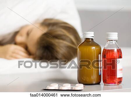 Girl lying in bed, medicines by bed side in foreground View Large Photo Image Stock Image - Girl lying in bed, medicines by bed side in foreground. Fotosearch