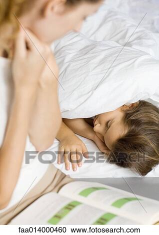Girl lying in bed, mother reading book to her View Large Photo Image Stock Image - Girl lying in bed, mother reading book to her. Fotosearch