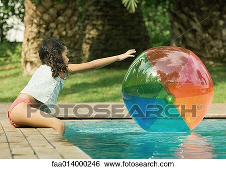 Girl sitting on edge of pool, reaching for beach ball in water View Large Photo Image Stock Photograph - Girl sitting on edge of pool, reaching for beach ball in water. Fotosearch