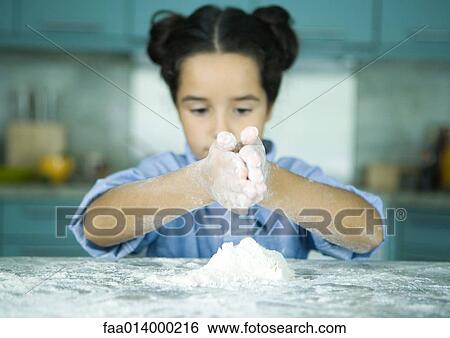 Girl standing at kitchen counter, holding hands over pile of flour View Large Photo Image Stock Photograph - Girl standing at kitchen counter, holding hands over pile of flour. Fotosearch