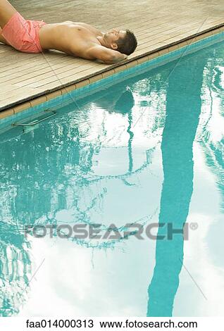 Man lying by edge of swimming pool View Large Photo Image Stock Image - Man lying by edge of swimming pool. Fotosearch