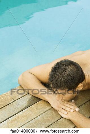 Man lying by edge of swimming pool View Large Photo Image Stock Photo - Man lying by edge of swimming pool. Fotosearch