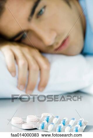 Man lying down, looking at packs of pills View Large Photo Image Stock Image - Man lying down, looking at packs of pills. Fotosearch