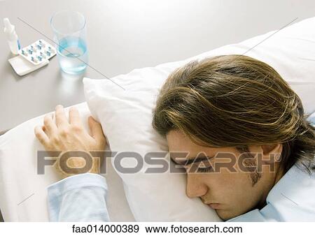 Man lying on bed, medicine by bed side View Large Photo Image Stock Photo - Man lying on bed, medicine by bed side. Fotosearch