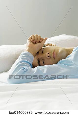 Man lying on bed with hand on forehead, eyes closed View Large Photo Image Stock Photograph - Man lying on bed with hand on forehead, eyes closed. Fotosearch