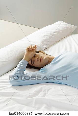 Man lying on bed with hand on forehead View Large Photo Image Stock Photography - Man lying on bed with hand on forehead. Fotosearch