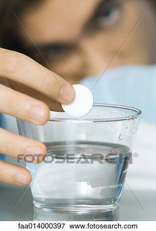 Man putting effervescent medicine into glass of water View Large Photo Image Stock Photo - Man putting effervescent medicine into glass of water. Fotosearch
