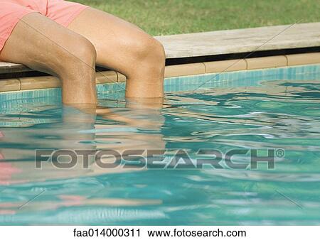Man sitting by edge of swimming pool with legs in water, cropped view View Large Photo Image Stock Image - Man sitting by edge of swimming pool with legs in water, cropped view. Fotosearch
