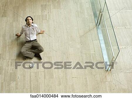 Man sitting on floor with coffee cup in front of him, leaning back, high angle view View Large Photo Image Picture - Man sitting on floor with coffee cup in front of him, leaning back, high angle view. Fotosearch