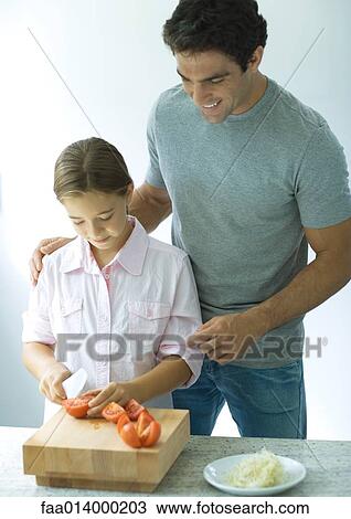 Man standing behind daughter as she cuts up tomatoes View Large Photo Image Stock Image - Man standing behind daughter as she cuts up tomatoes. Fotosearch