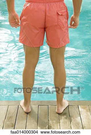 Man standing by edge of swimming pool, waist down View Large Photo Image Picture - Man standing by edge of swimming pool, waist down. Fotosearch