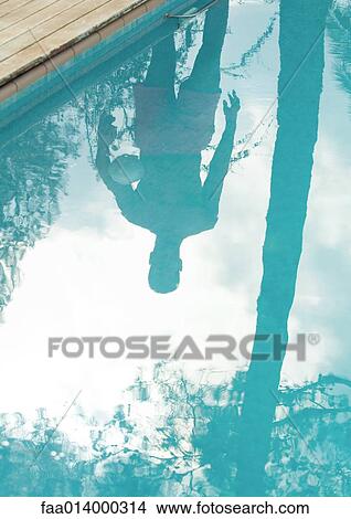 Man standing by edge of swimming pool, reflected in surface of water View Large Photo Image Picture - Man standing by edge of swimming pool, reflected in surface of water. Fotosearch