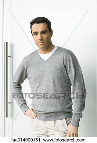 Stock Image - Man standing with hand on hip, looking at camera, portrait. Fotosearch