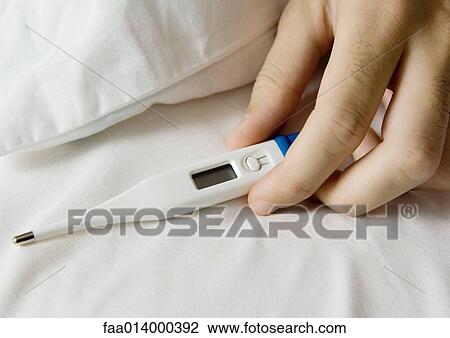 Man's hand holding thermometer on bed View Large Photo Image Stock Image - Man's hand holding thermometer on bed. Fotosearch