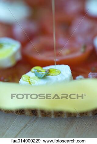 Olive oil being drizzled on uncooked tomato, goat cheese and ham tart View Large Photo Image Stock Photo - Olive oil being drizzled on uncooked tomato, goat cheese and ham tart. Fotosearch