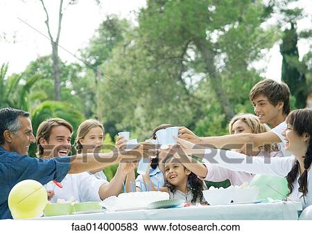 Outdoor birthday party attended by multi-generational family, everyone clinking cups View Large Photo Image Stock Image - Outdoor birthday party attended by multi-generational family, everyone clinking cups. Fotosearch