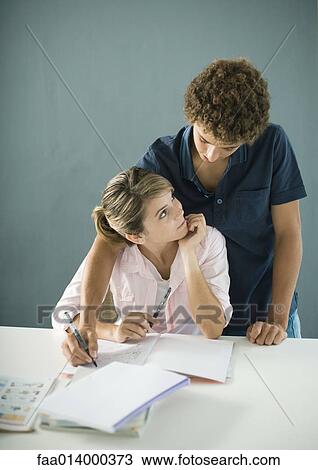 Teenage boy and girl doing homework together, boy reaching over girl's shoulder View Large Photo Image Stock Image - Teenage boy and girl doing homework together, boy reaching over girl's shoulder. Fotosearch