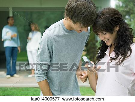 Teenage boy and girl looking at cell phone together View Large Photo Image Stock Photo - Teenage boy and girl looking at cell phone together. Fotosearch