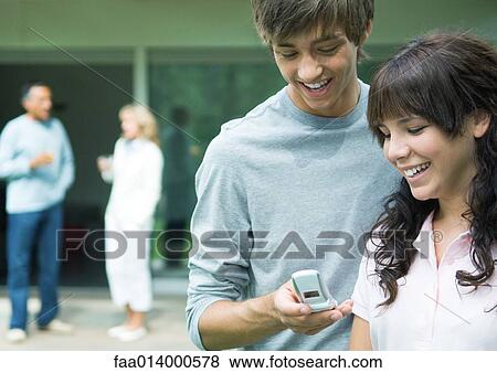 Teenage boy and girl looking at cell phone together View Large Photo Image Stock Photo - Teenage boy and girl looking at cell phone together. Fotosearch