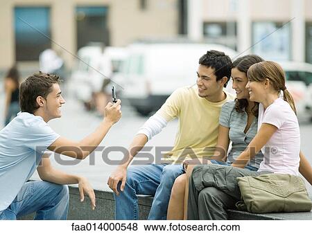 Teenage boy taking photo of friends with cell phone View Large Photo Image Stock Photo - Teenage boy taking photo of friends with cell phone. Fotosearch