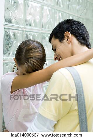 Teenage couple standing with arms around each other, girl hiding face View Large Photo Image Stock Photo - Teenage couple standing with arms around each other, girl hiding face. Fotosearch
