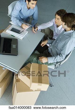 Three male colleagues grouped around desk, surrounded by cardboard boxes View Large Photo Image Stock Image - Three male colleagues grouped around desk, surrounded by cardboard boxes. Fotosearch