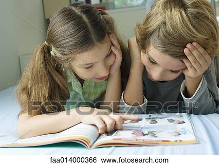 Two children looking at book together View Large Photo Image Stock Photograph - Two children looking at book together. Fotosearch