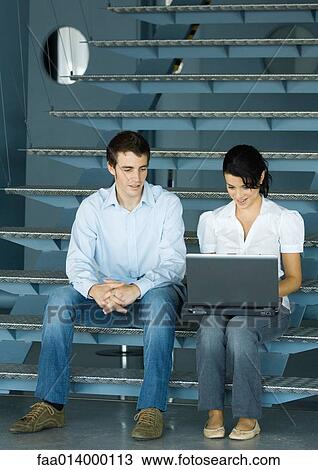 Two colleagues talking, sitting on stairs with laptop View Large Photo Image Stock Image - Two colleagues talking, sitting on stairs with laptop. Fotosearch