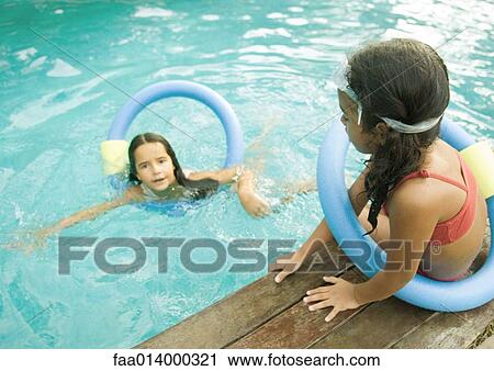 Two girls with floating rings, one in pool, one sitting on edge of pool View Large Photo Image Stock Image - Two girls with floating rings, one in pool, one sitting on edge of pool. Fotosearch