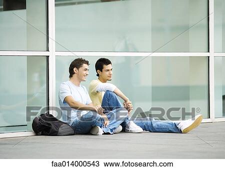 Two teenage boys sitting on ground in urban setting View Large Photo Image Stock Image - Two teenage boys sitting on ground in urban setting. Fotosearch