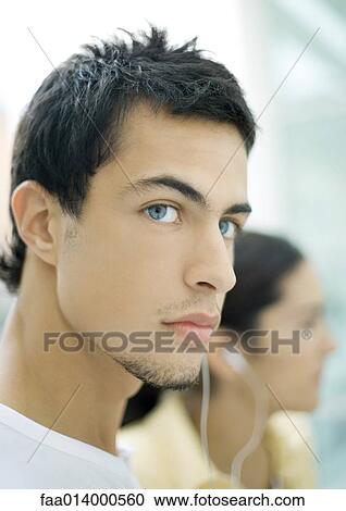 Two teenage friends sharing earphones, focus on young man in foreground View Large Photo Image Stock Image - Two teenage friends sharing earphones, focus on young man in foreground. Fotosearch
