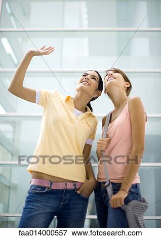 Two teenage girls looking up, one waving View Large Photo Image Stock Photo - Two teenage girls looking up, one waving. Fotosearch