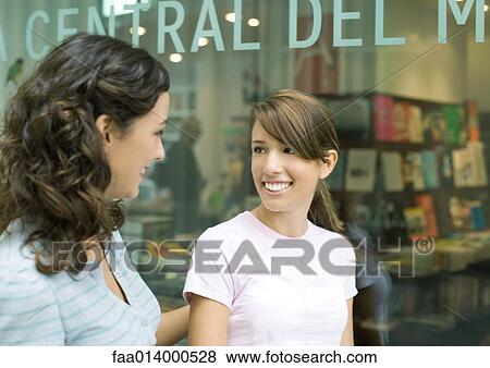 Two teenage girls standing in front of a bookshop View Large Photo Image Stock Photo - Two teenage girls standing in front of a bookshop. Fotosearch