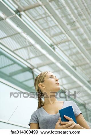 Woman holding agenda, structure in background, low angle view View Large Photo Image Stock Photo - Woman holding agenda, structure in background, low angle view. Fotosearch